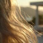 Mulher loira com cabelo brilhante e saudável em um ambiente de spa luxuoso em Balneário Camboriú, luz solar suave de fim de tarde, estética minimalista tons bege e dourado.